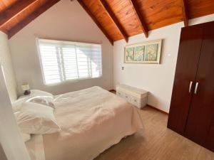 a bedroom with a white bed and a window at Dpto tipo cabaña en Pucón in Pucón