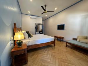 a bedroom with a bed with a ceiling fan and a couch at Sadakham Hotel in Luang Prabang
