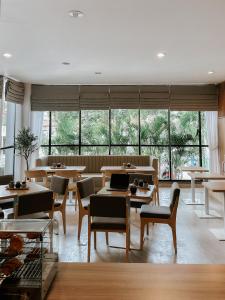 un restaurante con mesas, sillas y ventanas grandes en CASA CALMA HOTEL, en Yakarta