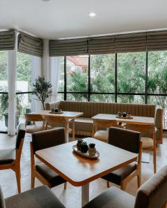 een restaurant met tafels en stoelen en grote ramen bij CASA CALMA HOTEL in Jakarta