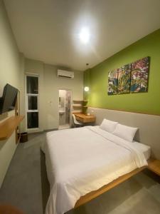een slaapkamer met een wit bed en een groene muur bij CASA CALMA HOTEL in Jakarta