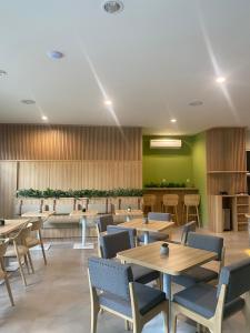 un restaurante con mesas y sillas de madera y paredes verdes en CASA CALMA HOTEL en Yakarta