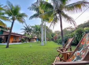 un par de sillas sentadas en un patio con palmeras en Residencial Alto do Arraial, en Arraial d'Ajuda