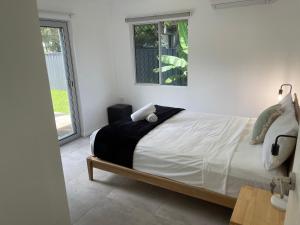 Schlafzimmer mit einem Bett mit weißer Bettwäsche und einem Fenster in der Unterkunft Cairns / Edge Hill Stylish Villa A in Edge Hill