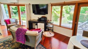 a living room with two chairs and a television at Moon Gate Villa in Kerikeri