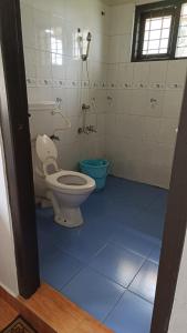 a bathroom with a toilet and a blue tile floor at The Four Seasons in Kalpetta