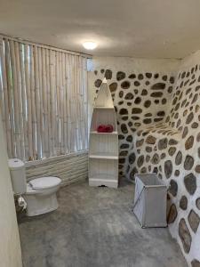 baño con aseo y pared de piedra en Villa Kingdome - 1 Bedroom, en Teluknarat