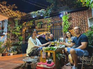 a group of people sitting at a table in a garden at Amazing House in Buôn Ðũng