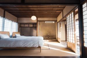 een slaapkamer met een bed in een kamer met ramen bij taos 丹波の風土を感じられる一棟貸切の宿 in Sasayama