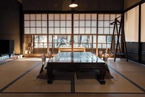 een eetkamer met een tafel en stoelen en een raam bij taos 丹波の風土を感じられる一棟貸切の宿 in Sasayama