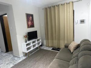 a living room with a couch and a television at Casa Inteira Aparecida - com escada - Vovó Zezé in Aparecida