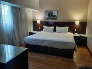 una habitación de hotel con una cama grande con sábanas blancas en WYND BERRINI SP, en São Paulo