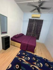 a bedroom with a purple bed and a ceiling fan at DakNan Homestay Duyong in Malacca