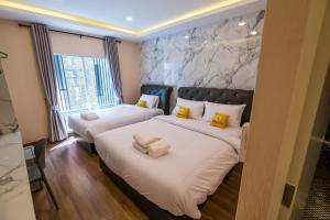 a bedroom with two beds with white sheets and yellow pillows at Amber Inn in Bangkok