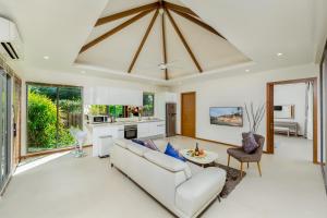 a living room with a white couch and a kitchen at Laem Ka Residence by Tropiclook in Rawai Beach