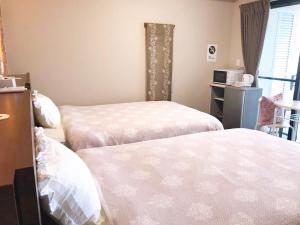 1 dormitorio con 2 camas con sábanas blancas en 月の道テラス, en Motobu