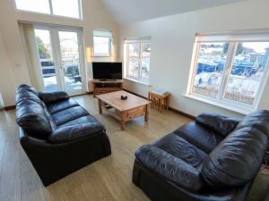 a living room with a leather couch and a coffee table at Moorings House in Fritton Norfolk