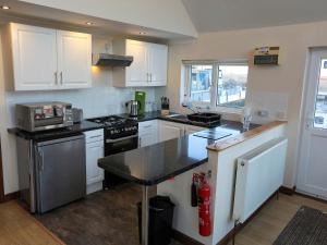 a kitchen with white cabinets and a black counter top at Moorings House in Fritton Norfolk