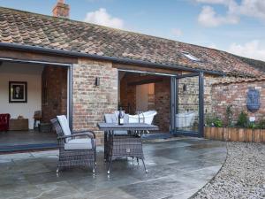 a patio with a table and chairs in front of a building at Sunset Barn - Uk12855 in Normanby