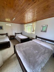 1 Schlafzimmer mit 2 Betten und Holzdecke in der Unterkunft Secretos del Carriel Finca Cafetera in Quimbaya