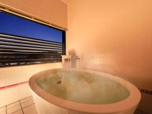 a bath tub in a bathroom with a large window at Hotel Tsubakino in Yamanouchi