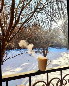a coffee cup sitting on a balcony in the snow at Sweet Vibe Home in Almaty