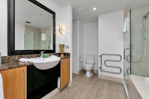 a bathroom with a sink and a shower and a toilet at The Golden Hour Penthouse in Auckland +19 photos
