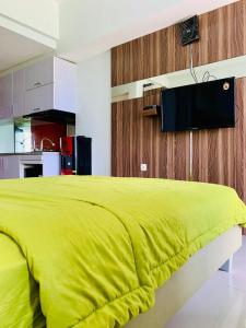a bedroom with a yellow bed and a kitchen at Apartemen Mahogany By Ruang Sultan in Karawang