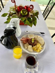 uma mesa branca com um prato de comida e uma bebida em Hotel Real Alaska em Liberia