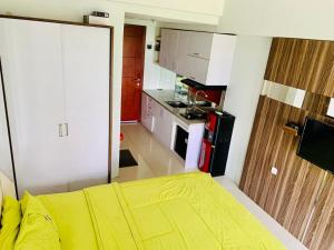a small kitchen with a yellow bed in a room at Apartemen Mahogany By Ruang Sultan in Karawang
