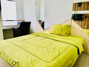 a bedroom with a yellow bed with a yellow blanket at Apartemen Mahogany By Ruang Sultan in Karawang