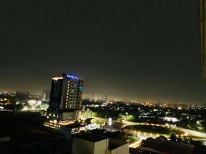 Apartemen Mahogany By Ruang Sultan في كراوانغ: أفق المدينة في الليل مع مبنى طويل