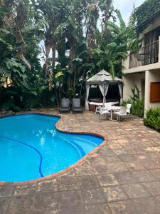 uma piscina num quintal com cadeiras e um guarda-sol em FernIvy Guest House em Pretoria