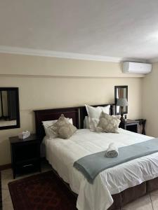 um quarto com uma cama grande com lençóis brancos e almofadas em FernIvy Guest House em Pretoria