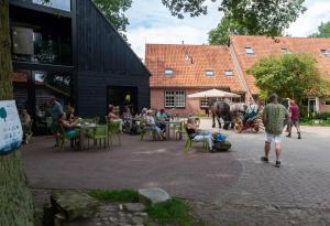 een groep mensen die aan tafels buiten een gebouw zitten bij Hoeve Springendal in Ootmarsum