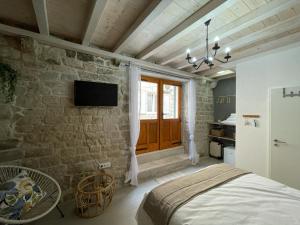a bedroom with a bed and a stone wall at Knez apartments and rooms in Kaštela