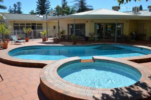 uma piscina com um pátio e uma casa em Glenelg Motel em Adelaide