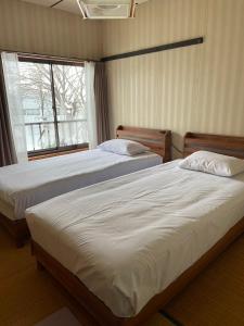 2 camas individuales en un dormitorio con ventana en 貸別荘バーンタイ戸狩 en Togari