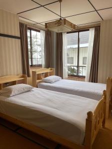two beds in a room with two windows at 貸別荘バーンタイ戸狩 in Togari