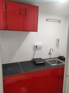 a kitchen with red cabinets and a sink at Sand and Wood premium cottage palolem beach in Canacona