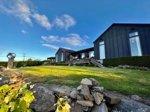 a black house on a grassy yard with rocks at 340 deg Alps & Sea in Christchurch