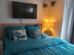 a bed with a blue comforter and a flat screen tv at CITY PREMIUM Studio Suite in Blankenberge