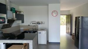 a kitchen with a refrigerator and a clock on the wall at Aranya Resort Koh Lanta in Ko Lanta