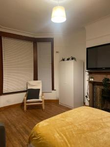 a bedroom with a bed and a chair and a flat screen tv at Balham, South London Spacious Guest House 1 in London