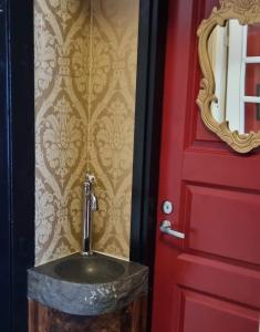 a bathroom with a sink next to a red door at Wanha Neuvola Guesthouse in Pieksamaki