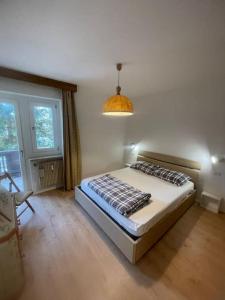 um quarto com uma cama e uma luz pendente em Appartamento a Dobbiaco nel cuore delle Dolomiti em Dobbiaco