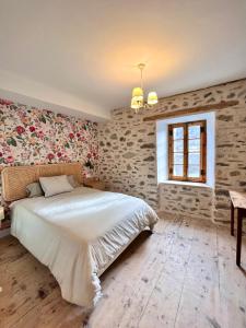 um quarto com uma grande cama branca e uma parede de tijolos em Hostel Baqueira - Refugi Rosta - PyrenMuseu em Salardú