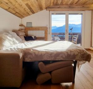 Cette chambre comprend un grand lit et une grande fenêtre. dans l'établissement Attique - vue plongeante sur le lac de la Moubra, à Crans-Montana