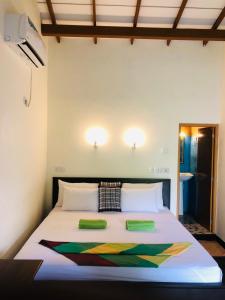 a bedroom with a bed with two green pillows on it at Sigiri Liya Rest in Sigiriya