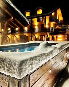 a hot tub covered in snow in front of a building at Chalet du Lys Hotel & SPA in Gressoney-la-Trinité